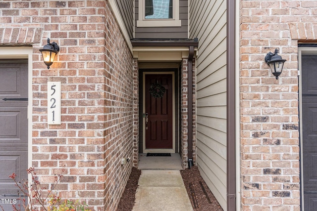 property entrance with a garage and brick siding