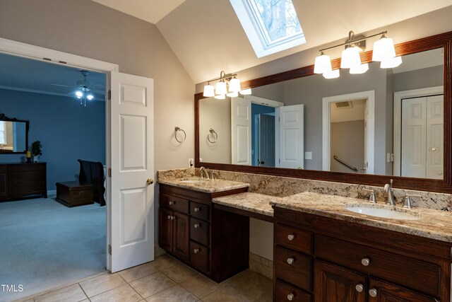 bathroom featuring a sink, lofted ceiling with skylight, double vanity, and tile patterned flooring