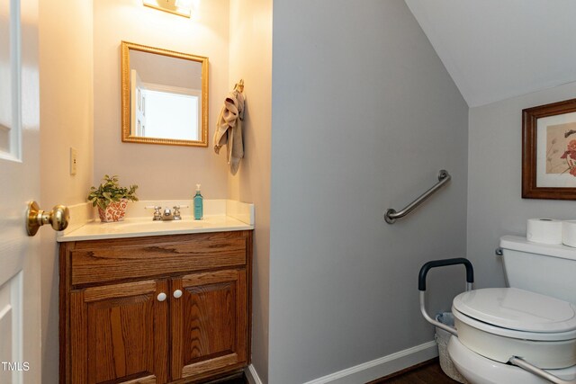 bathroom featuring baseboards, lofted ceiling, toilet, and vanity