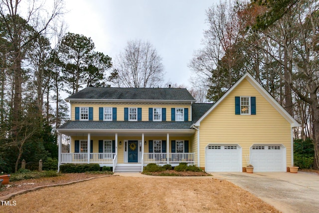 colonial house featuring a porch, a shingled roof, driveway, and an attached garage