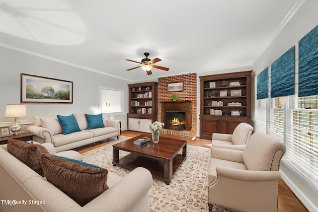 living room with wood finished floors, a brick fireplace, baseboards, ceiling fan, and ornamental molding
