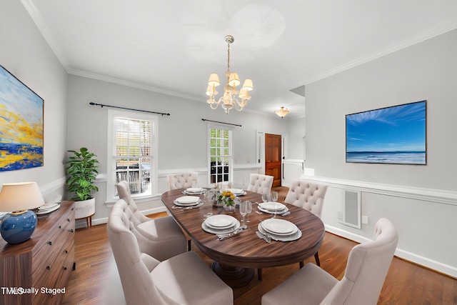 dining room featuring wood finished floors, ornamental molding, visible vents, a chandelier, and baseboards