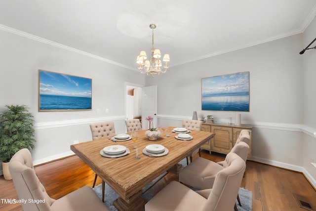dining area featuring crown molding, wood finished floors, baseboards, and an inviting chandelier