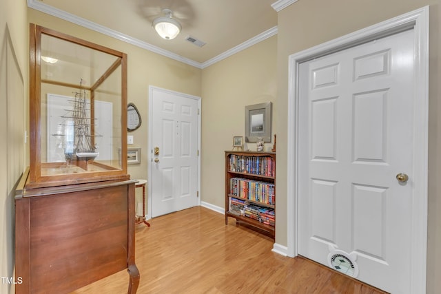 foyer entrance with light wood-style floors, baseboards, visible vents, and crown molding