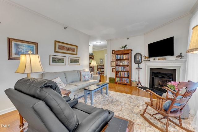 living area featuring baseboards, wood finished floors, a fireplace with flush hearth, and crown molding