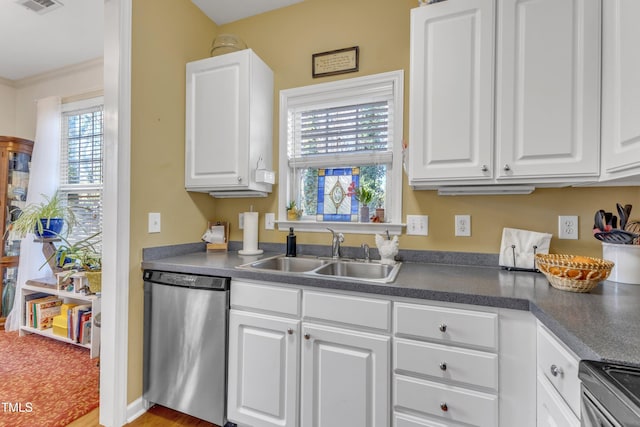 kitchen featuring dark countertops, white cabinetry, appliances with stainless steel finishes, and a sink