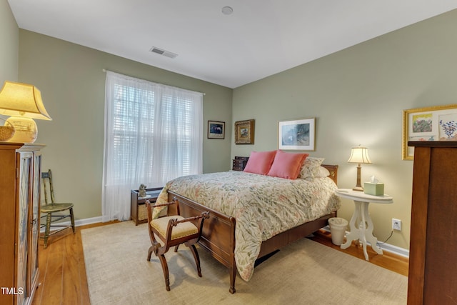 bedroom with light wood-style flooring, visible vents, and baseboards