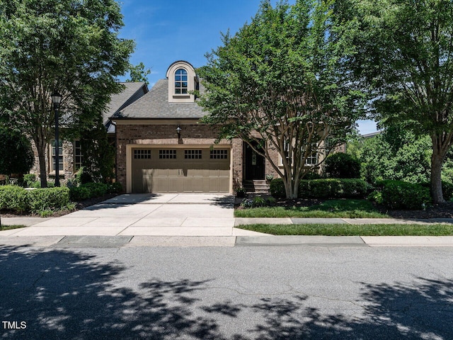 view of front of property with driveway, an attached garage, and brick siding