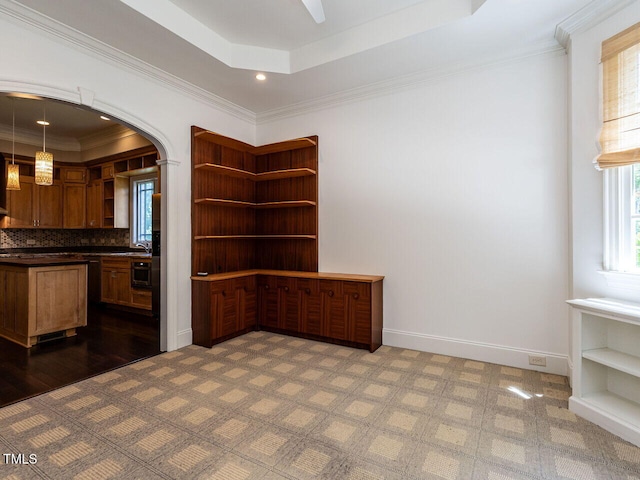 unfurnished dining area with a raised ceiling, arched walkways, ornamental molding, recessed lighting, and baseboards