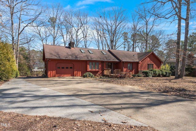 view of front of home with a garage, driveway, a chimney, and board and batten siding