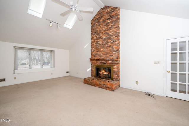 unfurnished living room featuring a skylight, carpet, a brick fireplace, and visible vents