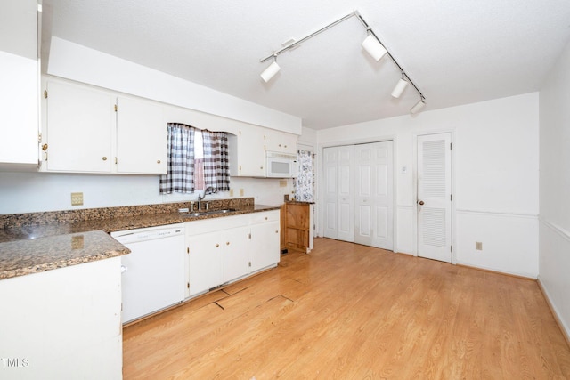 kitchen with white appliances, light wood-style flooring, white cabinets, and a sink