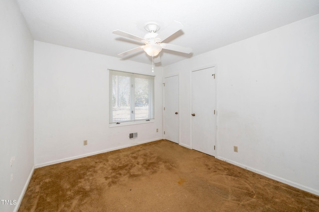 unfurnished bedroom featuring multiple closets, visible vents, carpet flooring, ceiling fan, and baseboards