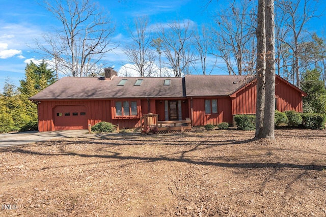 view of front of property featuring a garage, a shingled roof, dirt driveway, a chimney, and board and batten siding