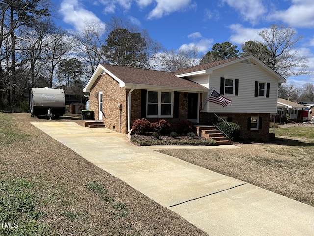 tri-level home with concrete driveway, brick siding, and roof with shingles