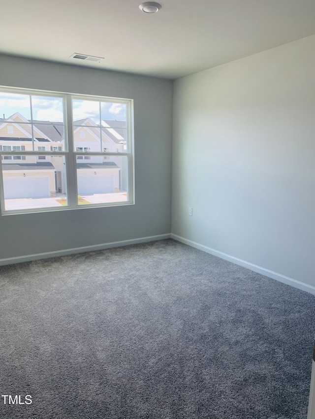 spare room with a wealth of natural light, visible vents, and carpet flooring