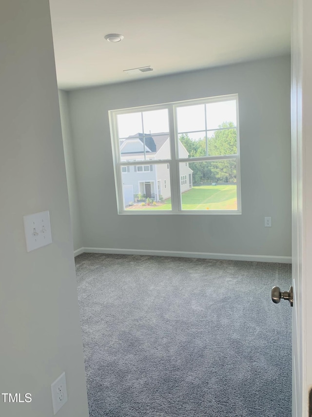 empty room with carpet flooring, visible vents, and baseboards