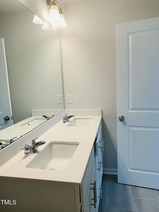 full bath with double vanity, baseboards, and a sink