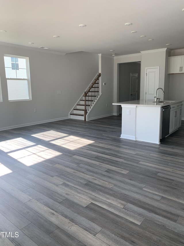 unfurnished living room featuring ornamental molding, dark wood-style flooring, a sink, and stairs