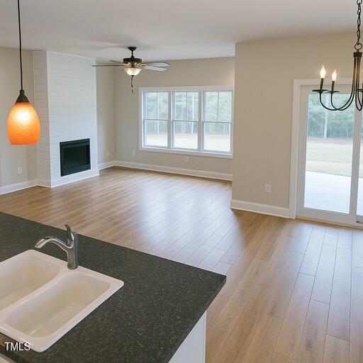 148 Mohawk Dr, Louisburg, NC 27549 - kitchen with ceiling fan, a chandelier, wood finished floors, decorative light fixtures, and a large fireplace