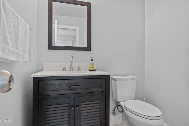 bathroom with vanity, toilet, baseboards, and tile patterned flooring