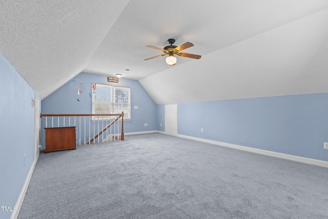 additional living space featuring baseboards, carpet floors, ceiling fan, vaulted ceiling, and a textured ceiling