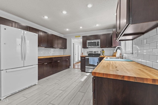 kitchen with light wood-type flooring, a sink, stainless steel appliances, butcher block counters, and dark brown cabinets