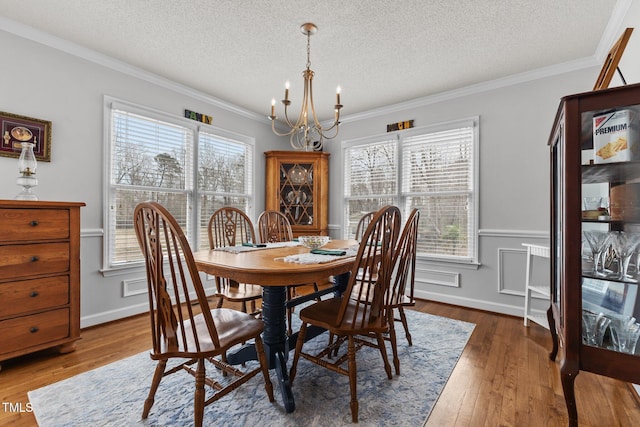 dining area with a textured ceiling, crown molding, an inviting chandelier, and hardwood / wood-style floors