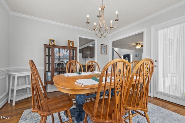 dining space with a notable chandelier, wood finished floors, wainscoting, and ornamental molding