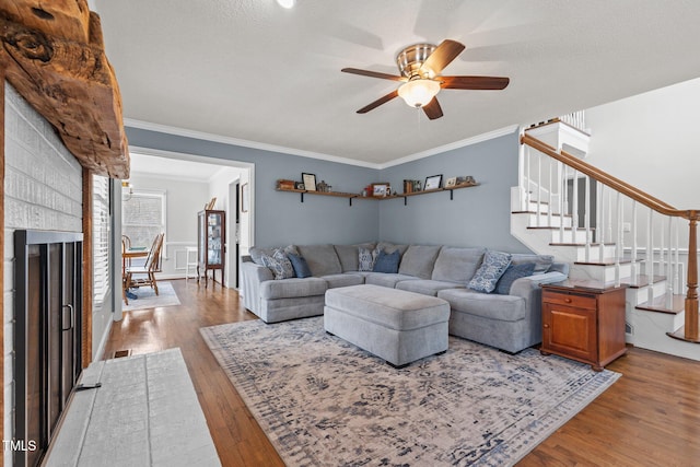 living area with visible vents, crown molding, stairway, wood finished floors, and a ceiling fan