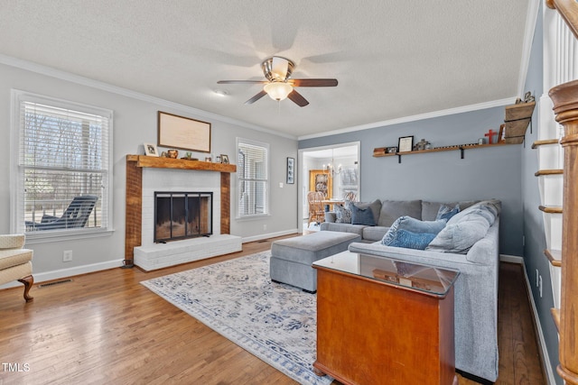 living room with visible vents, ornamental molding, a ceiling fan, a textured ceiling, and wood finished floors