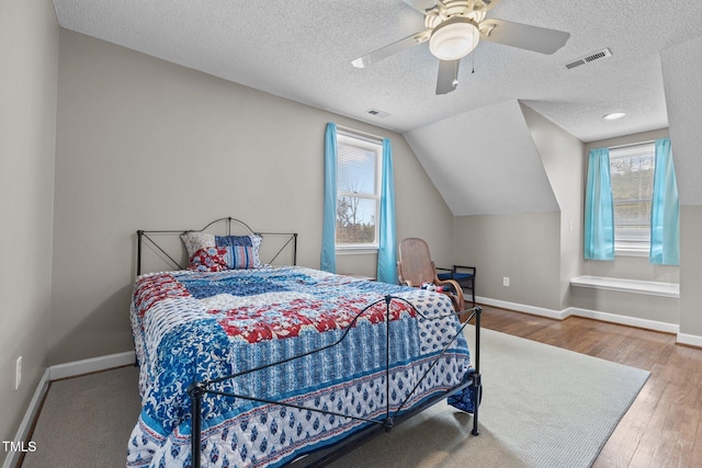 bedroom with visible vents, baseboards, wood finished floors, and vaulted ceiling