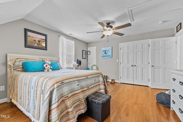 bedroom with a closet, a textured ceiling, attic access, and light wood-style flooring