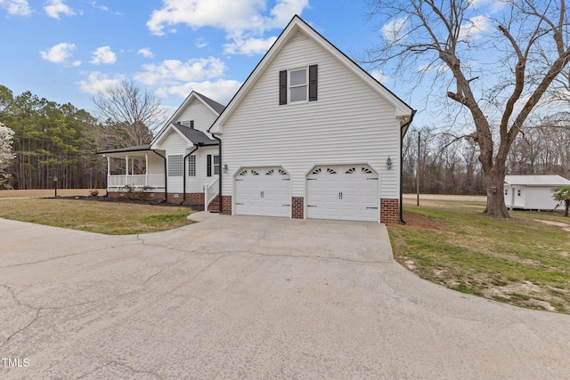 view of front of house featuring concrete driveway, an attached garage, covered porch, and a front yard