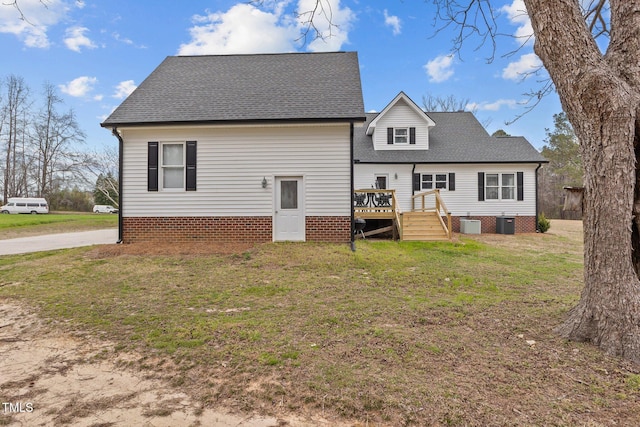 rear view of house with central air condition unit, a lawn, a shingled roof, and a deck