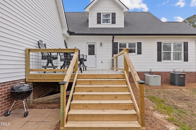 exterior space featuring a wooden deck, central AC, and roof with shingles