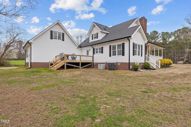 rear view of house with stairway, a lawn, central AC, and a chimney