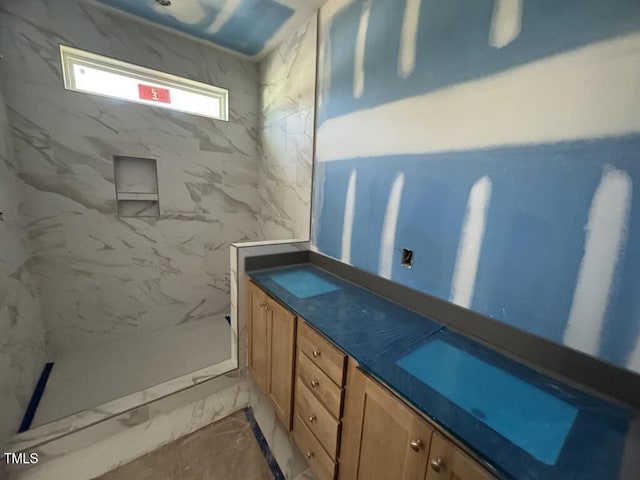 bathroom featuring marble finish floor, a marble finish shower, and vanity