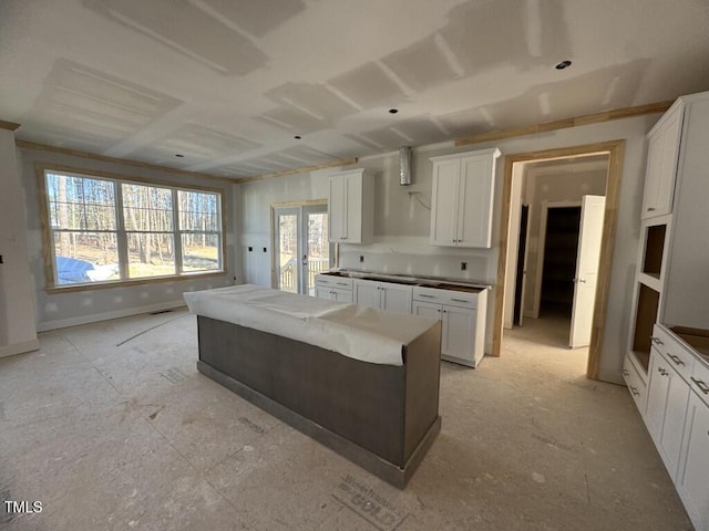 kitchen featuring baseboards, french doors, a kitchen island, and white cabinets