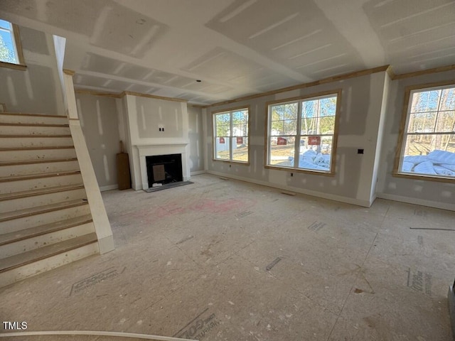 unfurnished living room with stairway, a fireplace, and baseboards