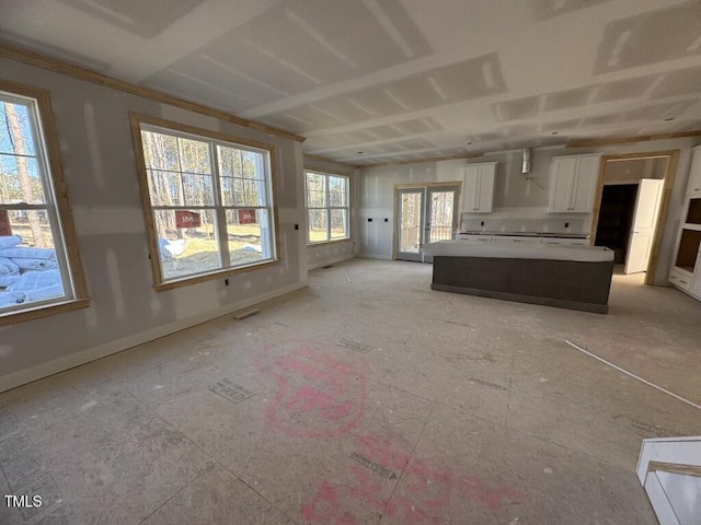 kitchen with visible vents, baseboards, white cabinets, light countertops, and a center island