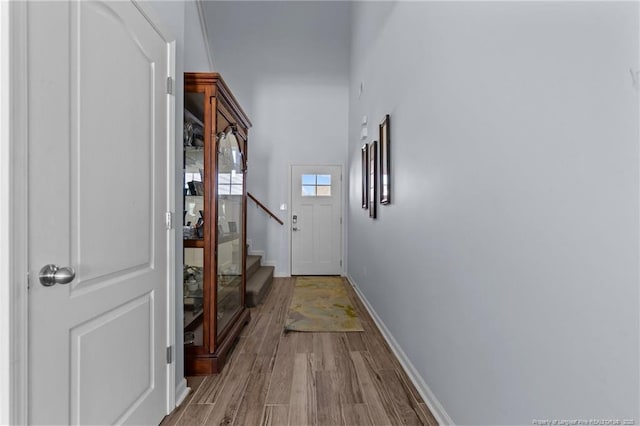 doorway with stairs, baseboards, and wood finished floors