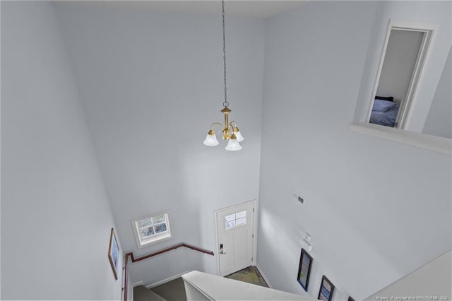 staircase with an inviting chandelier, a high ceiling, and visible vents