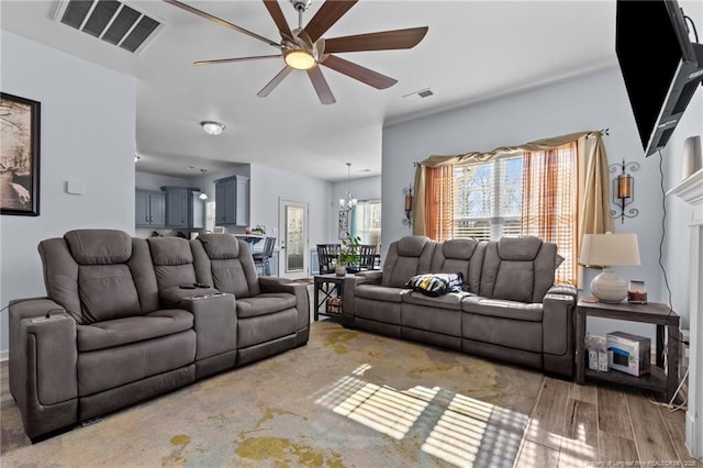 living area featuring ceiling fan with notable chandelier, wood finished floors, and visible vents