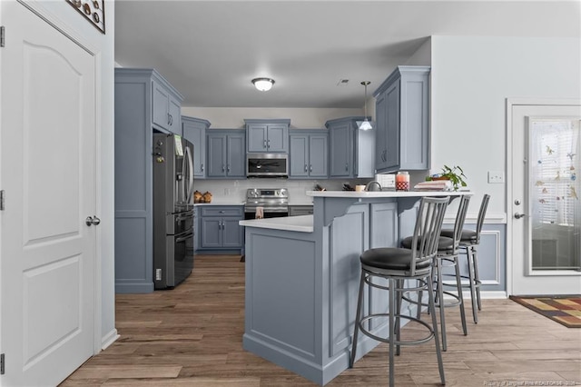 kitchen featuring a peninsula, a breakfast bar, stainless steel appliances, and wood finished floors