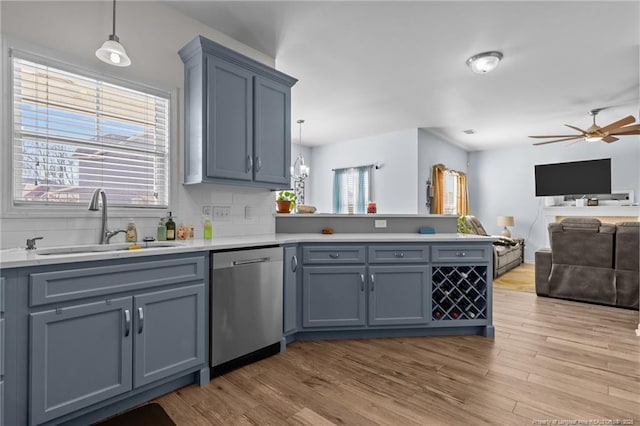 kitchen featuring a peninsula, stainless steel dishwasher, a sink, and a wealth of natural light