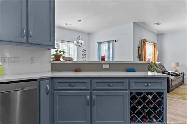 kitchen with a peninsula, visible vents, open floor plan, stainless steel dishwasher, and light wood finished floors