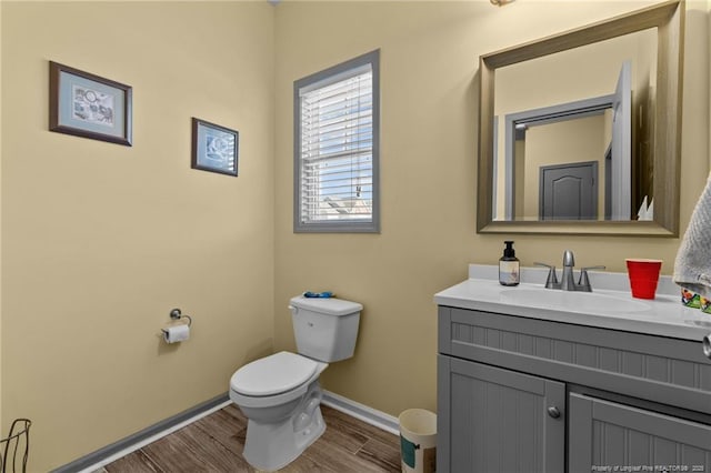 half bathroom featuring baseboards, vanity, toilet, and wood finished floors