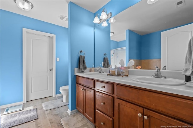 full bath with double vanity, wood finished floors, a sink, and visible vents