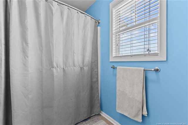 bathroom featuring curtained shower and baseboards